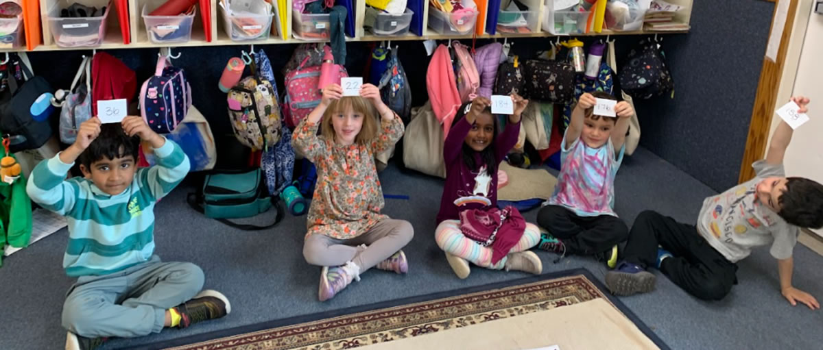 Children playing a game holding numbered index cards over their heads