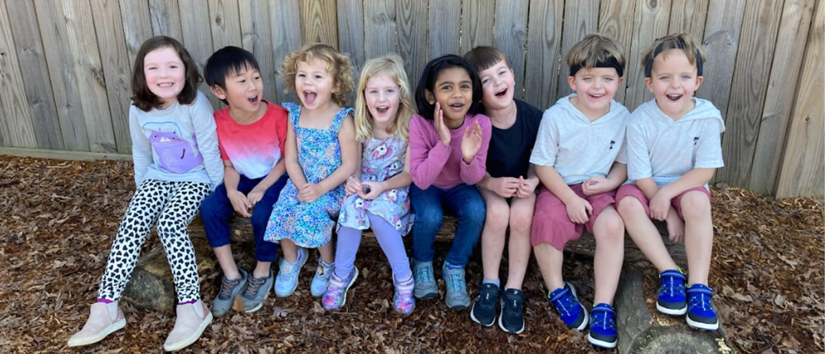 Children sitting against a wooden fence